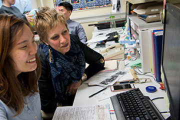 Instructor assisting an international student on a computer
