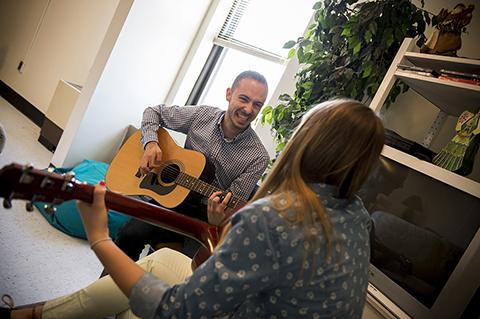 Man and woman smile and play guitars